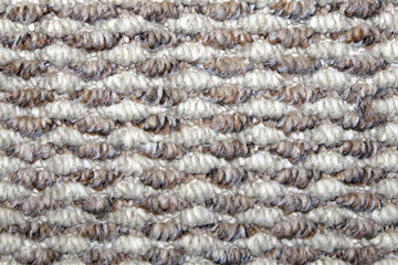 Beige and white synthetic floor carpet covering with wavy geometric pattern, may be used as background or texture