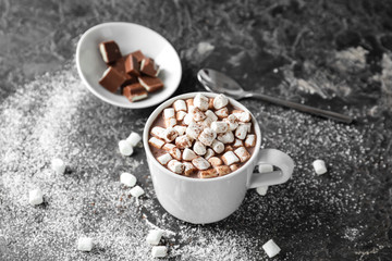 Cup of delicious cocoa with marshmallows and chocolate on grunge table