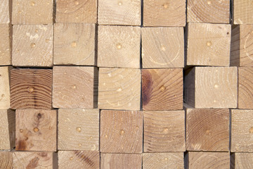 Light wooden bars with a square section stacked in a pile in even rows