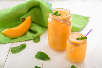 Jars of fresh melon smoothie on white  table