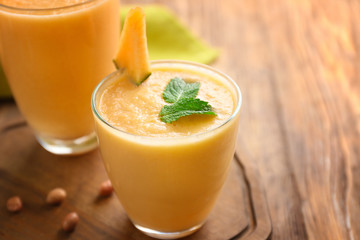 Glass with tasty melon smoothie on wooden table, closeup