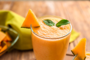 Glass with tasty melon smoothie on table, closeup