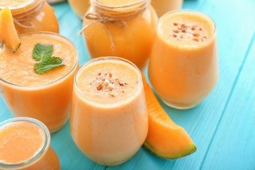 Jars and glasses with tasty melon smoothie on color table
