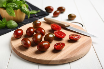 Board with delicious tomatoes on wooden table