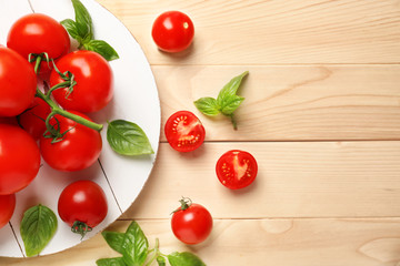 Board with delicious tomatoes and fresh basil on wooden table