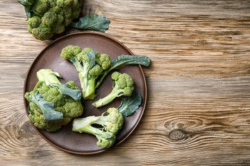 Plate with ripe broccoli on wooden table