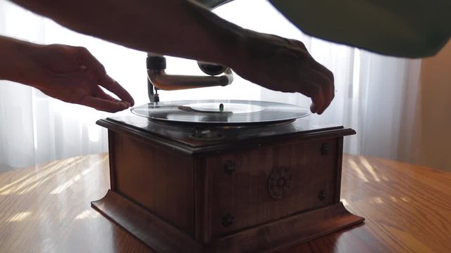 Place a record on an old antique record player Gramophone Phonograph to begin playing music.