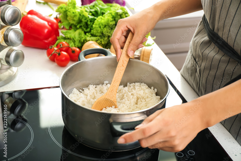 Wall mural woman cooking rice in saucepan on stove