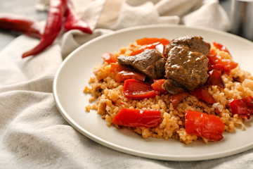 Plate with boiled rice, meat and pepper on table