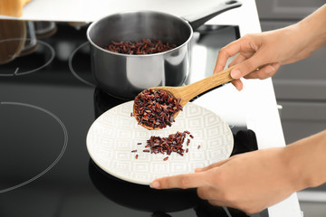 Woman putting boiled rice on plate