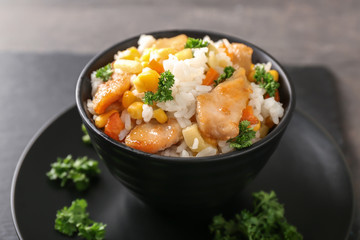 Bowl with boiled rice, meat and vegetables on table