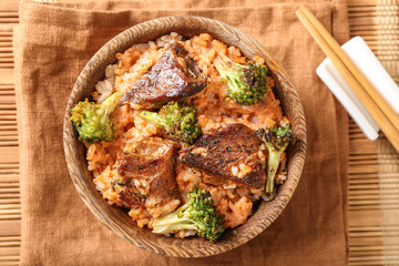 Bowl with boiled rice, meat and broccoli on table