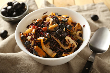 Bowl with boiled rice and seafood on table