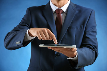 Businessman with tablet PC on color background
