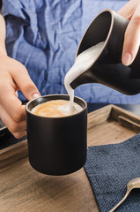 Female hands pouring  milk foam into espresso , Preparing, making cappuccino.