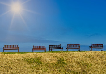 A row of benches on a sunny day with sun shining.