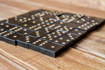 Black old, vintage dominoes on a wooden table closure. The concept of the game dominoes. Selective focus