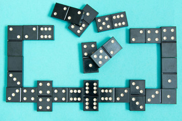 Black old, vintage dominoes on a  cardboard turquoise background. The concept of the game dominoes....