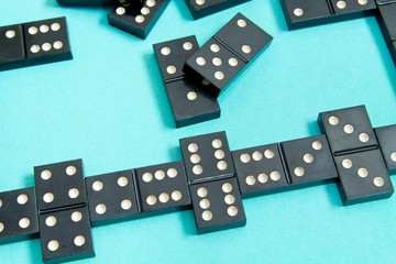 Black old, vintage dominoes on a  cardboard turquoise background. The concept of the game dominoes. Selective focus