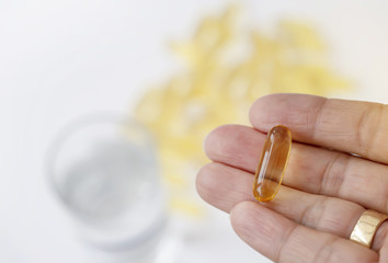 Close up old women hand showing fish oil capsule with blurry background,Take Vitamin Omega-3 fish oil one a day, A food supplements for elderly people, Healthy life concept