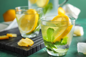 Glass of fresh lemonade on color table