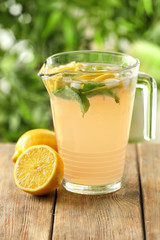 Jug of fresh lemonade on wooden table