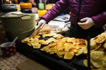 Theme is traditional street food in a European city on the market square in the Czech Republic Prague in the New Year's Eve, Christmas Eve festivities. Hands sell, prepare smoked cheese.