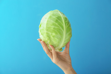 Woman holding fresh cabbage on color background