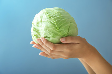 Woman holding fresh cabbage on color background