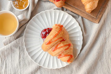 Tasty croissant with jam on plate