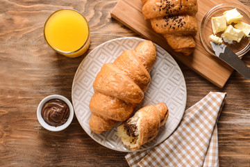 Tasty croissants with chocolate on wooden table