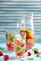 Glassware of fresh strawberry lemonade on color table
