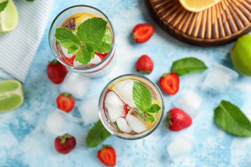 Glasses of fresh strawberry lemonade on color table