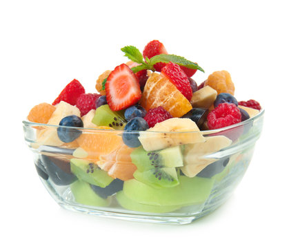 Delicious fruit salad in glass bowl on white background