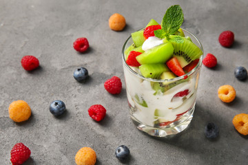 Delicious fruit salad in glass on grey table