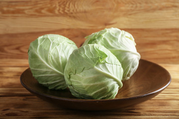 Plate with fresh cabbages on wooden table