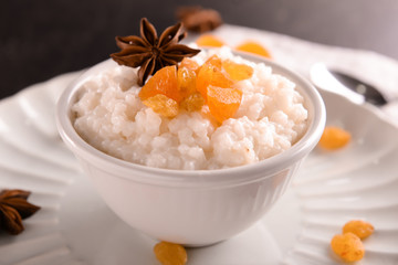 Delicious rice pudding with dried fruits and anise in bowl on plate