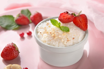 Delicious rice pudding with berries in bowl on color plate