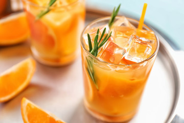 Glass of tasty orange cocktail on tray