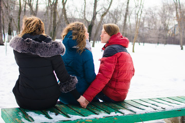 The concept of the image of marital infidelity. Young people on the bench, hugs one and hold the...