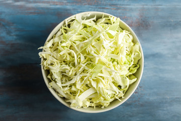 Bowl with shredded cabbage on wooden table