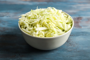 Bowl with shredded cabbage on wooden table
