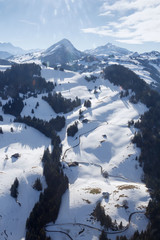 View from a helicopter to the mountains of the Swiss alps on a winter afternoon. Photo of nature with sunny hares in the backlight