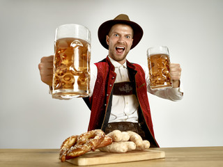 Germany, Bavaria, Upper Bavaria. The young happy smiling man with beer dressed in traditional...