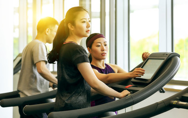 Asian professional female coach teaching little girls to use the treadmill correctly