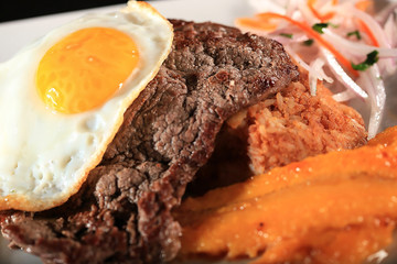 Peruvian traditional steak with fried egg an banana tacu tacu