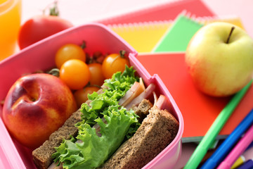 Lunch box with appetizing food and stationery on table, closeup