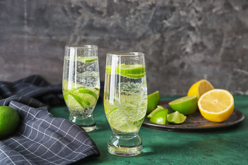 Glasses of fresh lime lemonade on color table