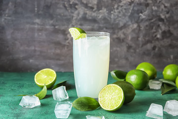 Glass of fresh lime lemonade on color table