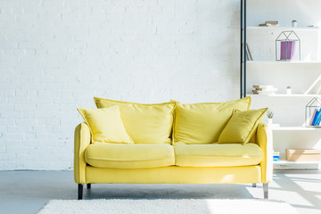 cozy yellow sofa with cushions in living room interior